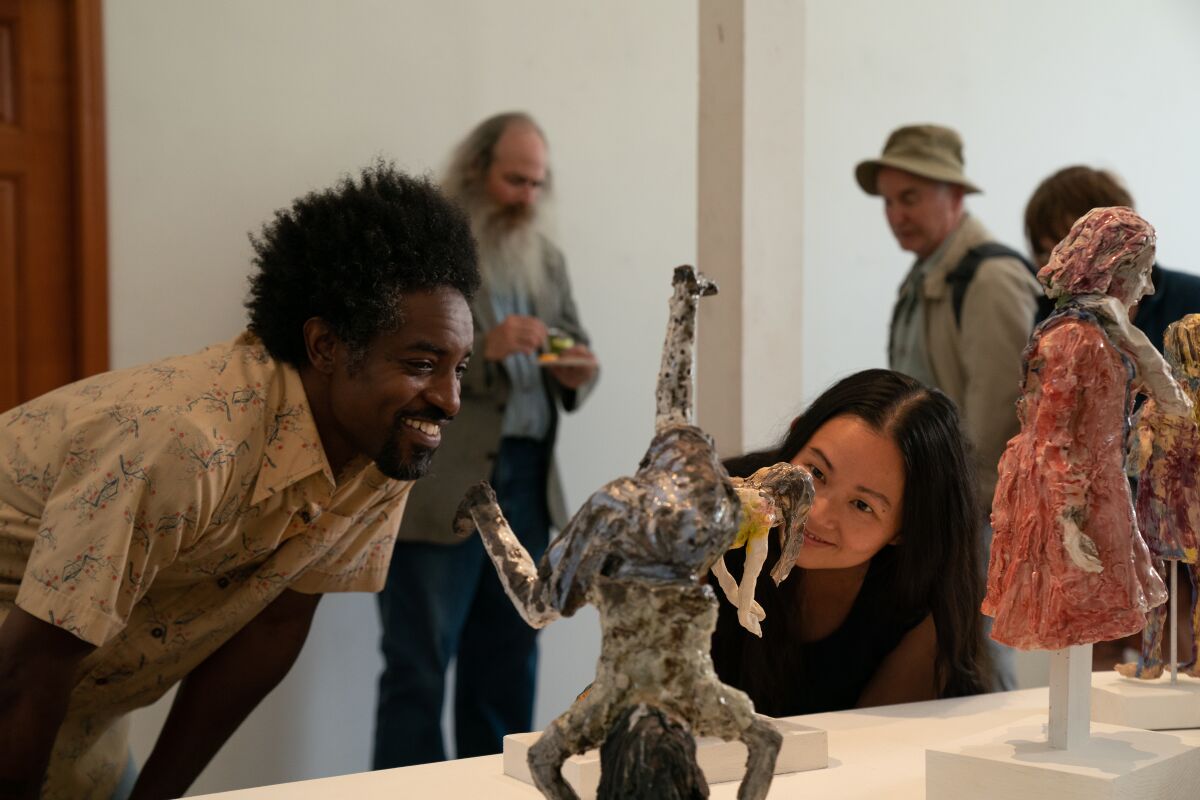 Two people bend down to examine a ceramic sculpture.