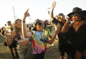 People in festive clothing hold up their hands at Coachella