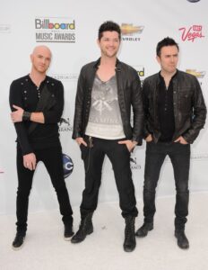 The Script's Mark Sheehan, Danny O'Donoghue and Glen Power standing on a red carpet.