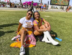 Danielle Veira and Gabrielle Veira sitting on the grass at Coachella 2023.