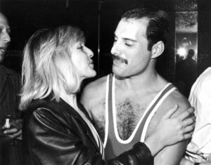 Mary Austin wearing leather jacket and Freddie Mercury in tank top embrace