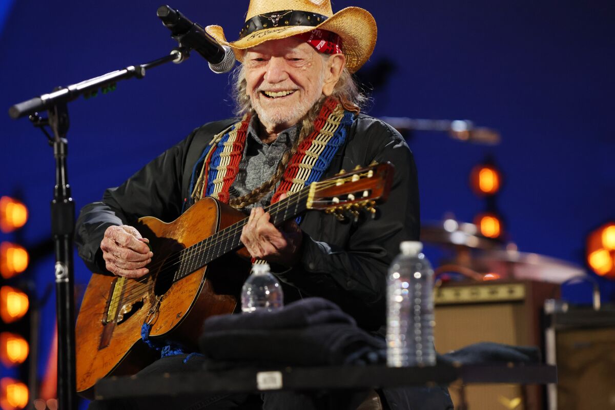 Willie Nelson performs with a wide grin.