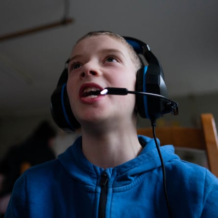 Harry Day, 12, speaks with other players online via a headset as he plays on his video game.