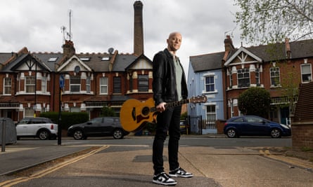 James Fox, Britain’s Eurovision entrant in 2004, standing in a street holding the guitar he played then
