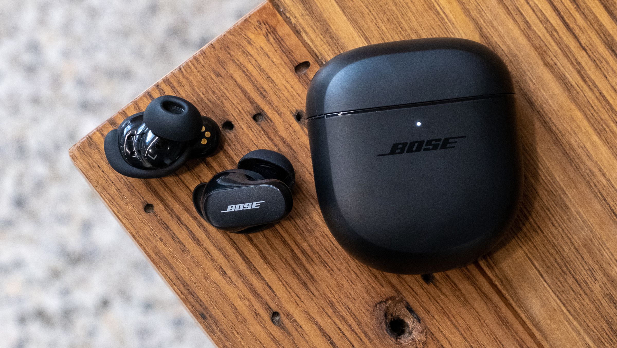 An overhead image of the Bose QuietComfort Earbuds II on a wood table.