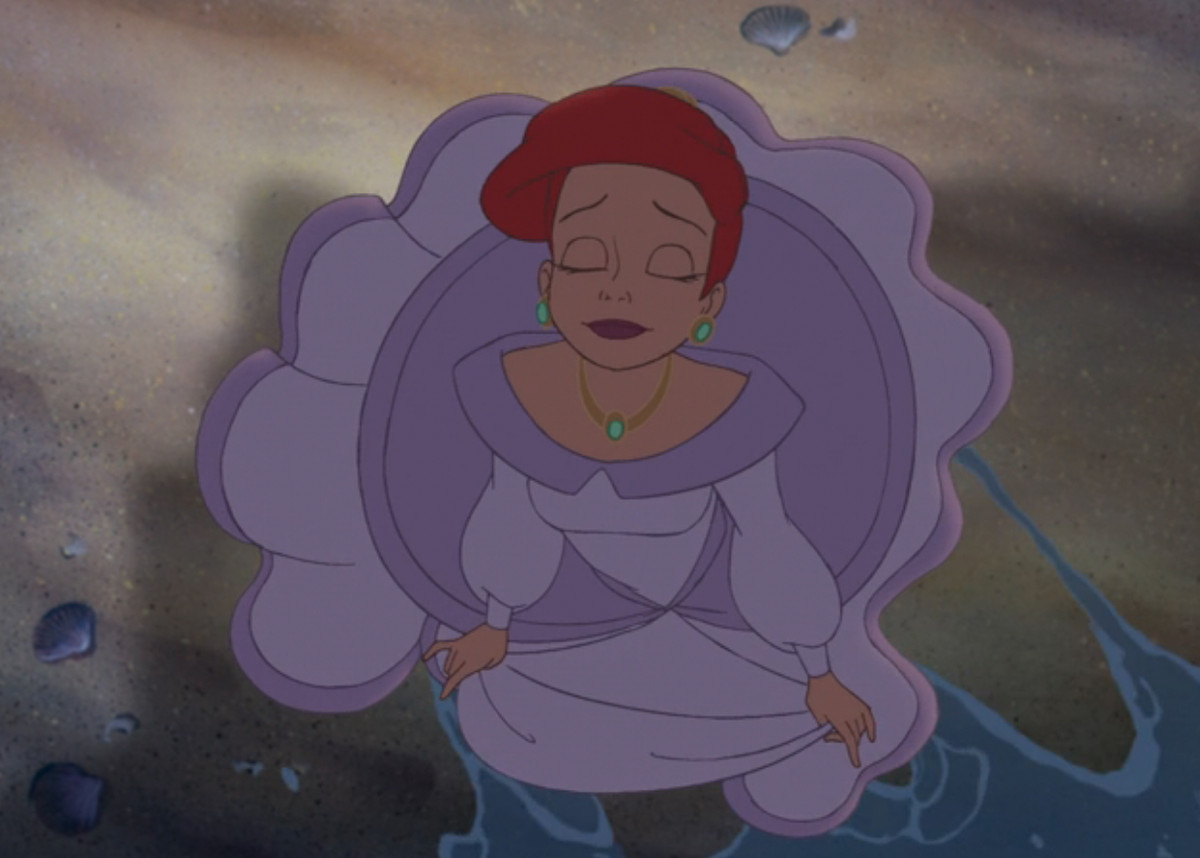 An adult Ariel closes her eyes and dips a foot in sea water