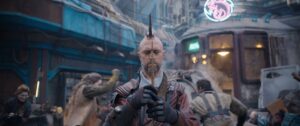 Bald, metal-mohawked space pirate Kraglin (Sean Gunn) stands with his eyes closed, holding an arrow up in front of him in a meditative posture, in Guardians of the Galaxy Vol. 3