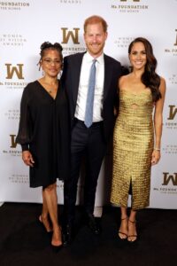 Doria Ragland, Prince Harry and Meghan pictured together on Tuesday night. The Duchess of Sussex wore a gold dress by Johanna Ortiz, and earrings by J. Crew.