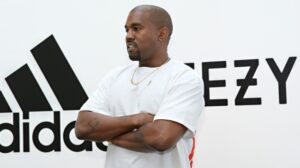 Kanye West standing in front of Adidas and Yeezy logos