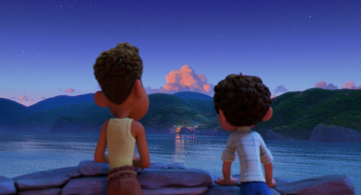 Luca and Alberto looking out at a town across the water in the evening