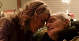 A woman touches her head to the forehead of an elderly man in the documentary "Last Flight Home."