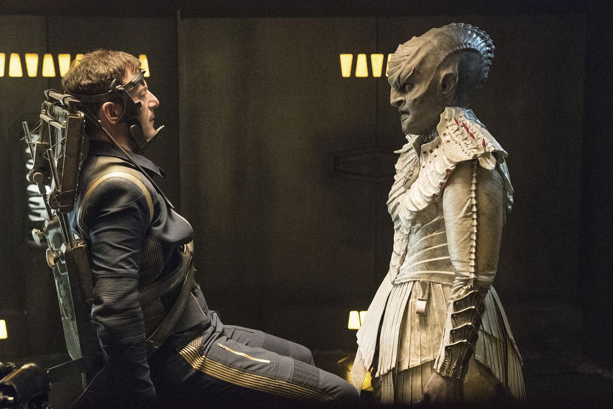 L’Rell (Mary Chieffo) interrogating a Star Fleet officer in a still from Star Trek Discovery. L’Rell is tall and gray and has a long, oblong head and forehead ridges, with a skull that resembles Geiger drawings