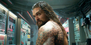 Jason Momoa standing in front of a control panel.