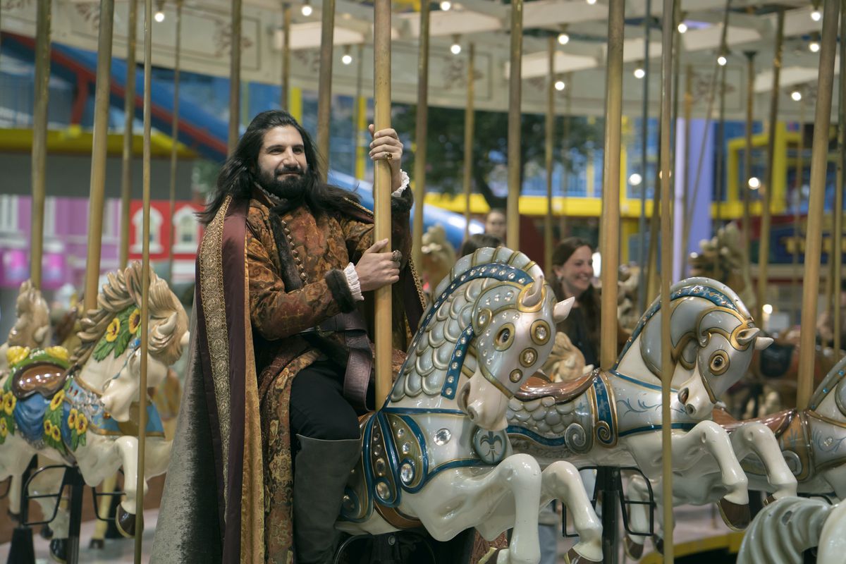 Nandor (Kayvan Novak) riding a merry-go-round, looking content