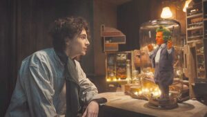 Timothee Chalamet and Hugh Grant as Willy Wonka and an Ooompa Loompa stare at each other in trailer