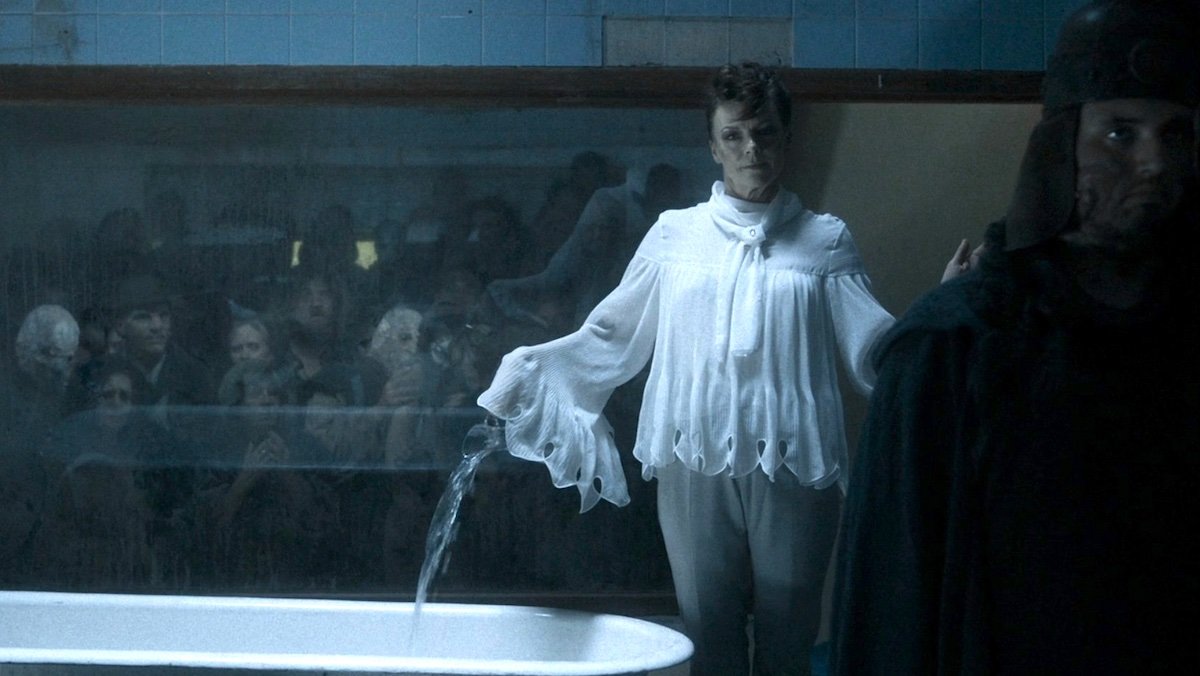An angel in all white purs holy water into a bathtub in Hell on Good Omens