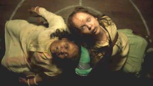 Image of two posessed girls with crosses cut into their foreheards staring up with yellow eyes in the exorcist believer trailer