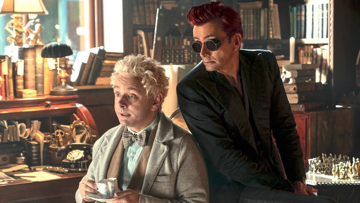 Aziraphale sitting in his chair with tea with Crowley sitting behind him on the arm on Good Omens