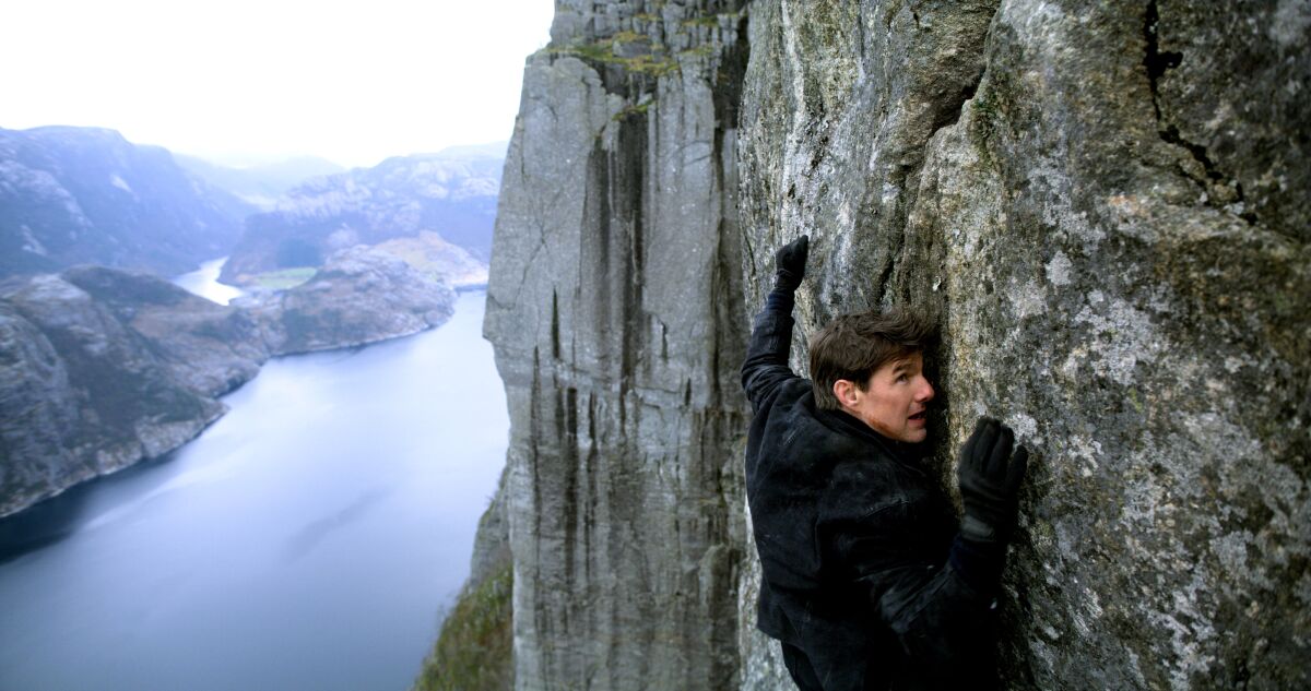 Tom Cruise hangs onto the sheer face of a mountain