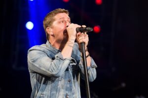 Matchbox Twenty frontman Rob Thomas sings directly into a microphone onstage.