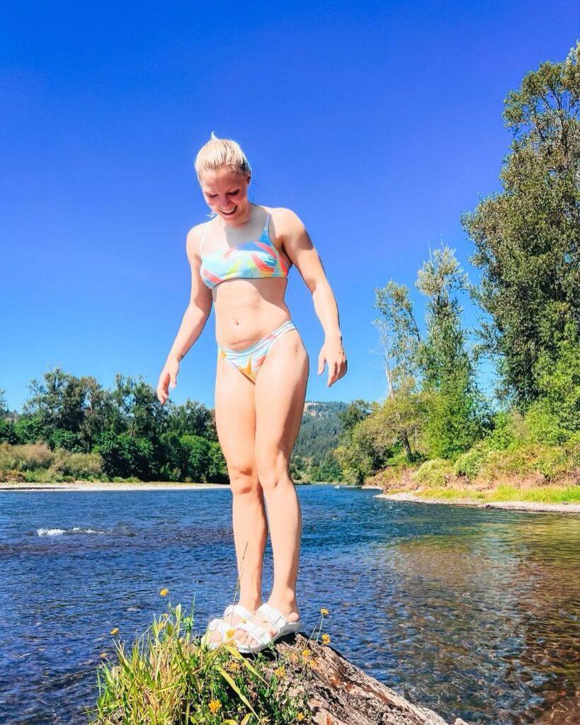 Jade Carey stands on a log while wearing a bikini.