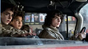Finn Wolfhard drives the Ecto-1 with McKenna Grace and Logan Kim in the backseat in Ghostbusters: Afterlife.