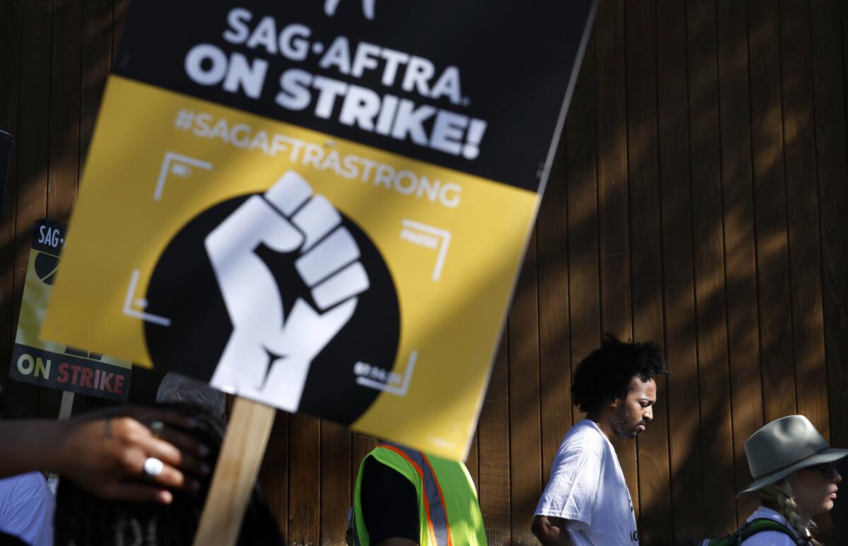 A person carries a poster in support of SAG-AFTRA