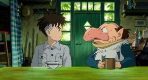 A boy and a man sit at a table with mugs in the movie "The Boy and the Heron."