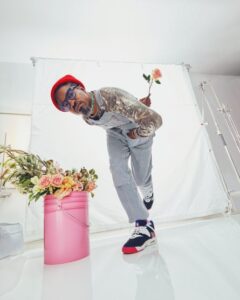 André 3000 holding a rose behind his back and posing for the camera