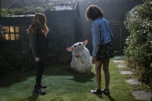 Donna and Rose stand in front of their shed looking at The Meep, a large weird Furby lookin alien from the Doctor Who special The Star Beast