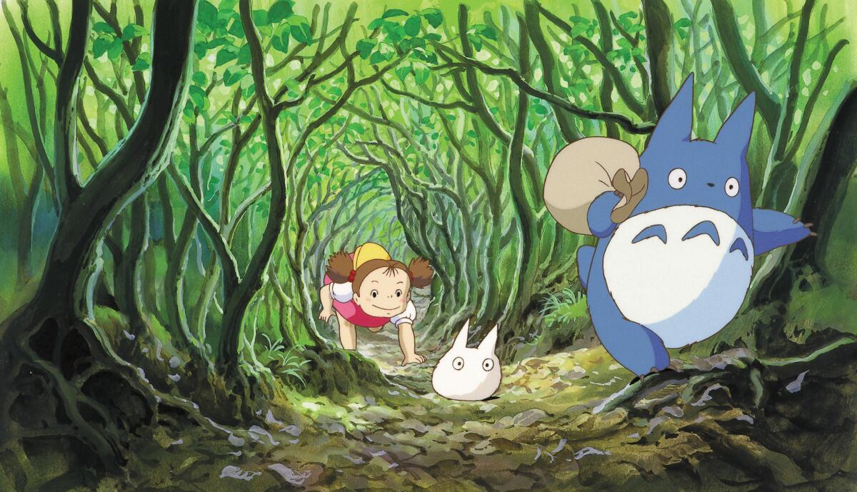 A girl chases two small creatures through a tunnel of trees in the animated film "My Neighbor Totoro."