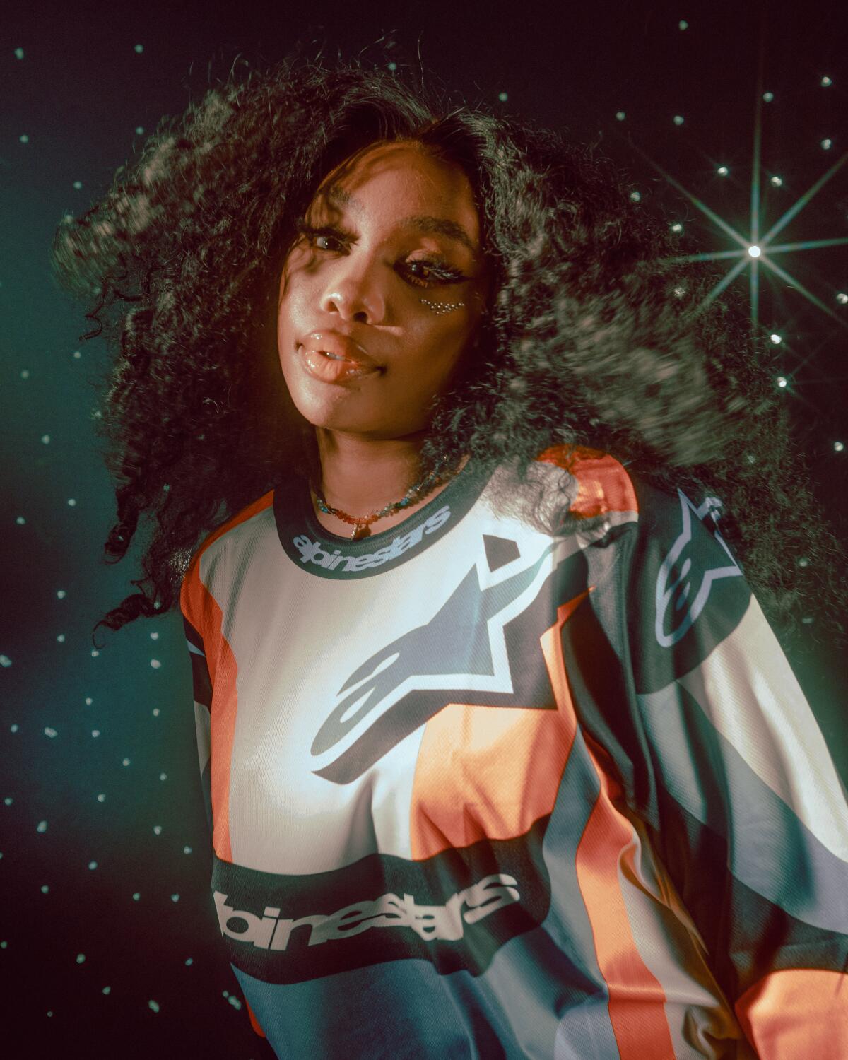 SZA is photographed in front of a celestial backdrop.
