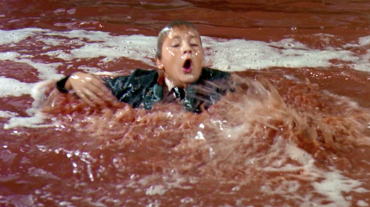 Augustus Gloop treads water and gasps for breath in a chocolate river in Willy Wonka and the Chocolate Factory