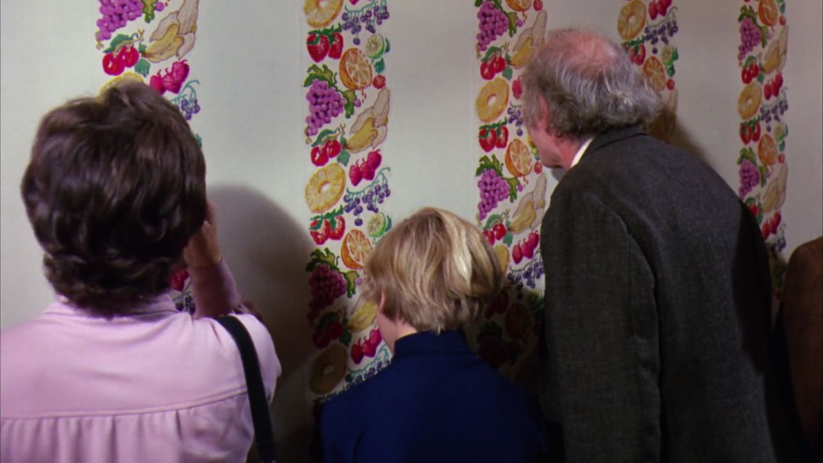 Charlie and Grandpa Joe licking the fruit-patterned wallpaper