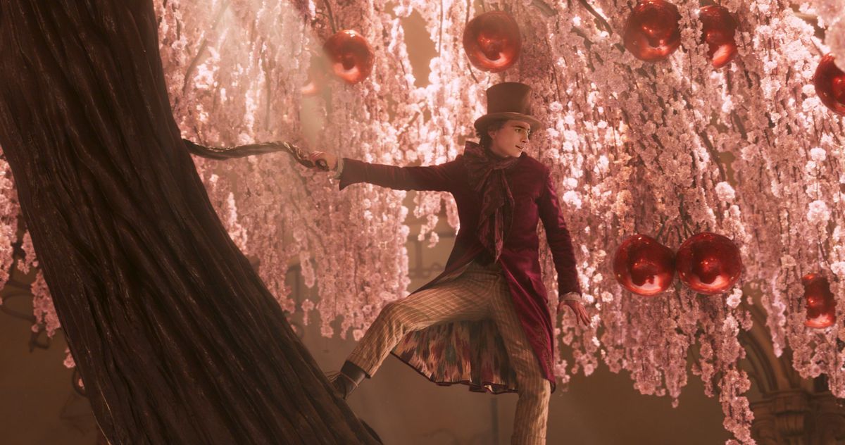 Timothee Chalamet’s Wonka standing on the trunk of a giant chocolate cherry blossom tree