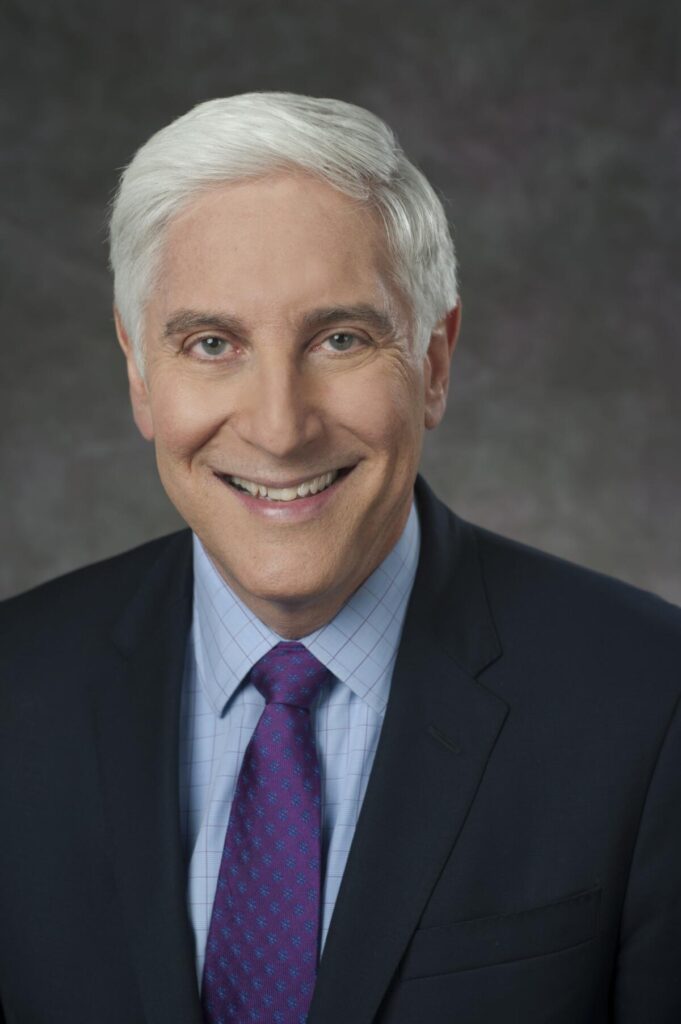 A headshot of Dr. Jon LaPook in a blazer and purple tie.