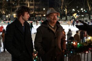 A bundled up young man and older man walk away from an ice skating rink in "The Holdovers."