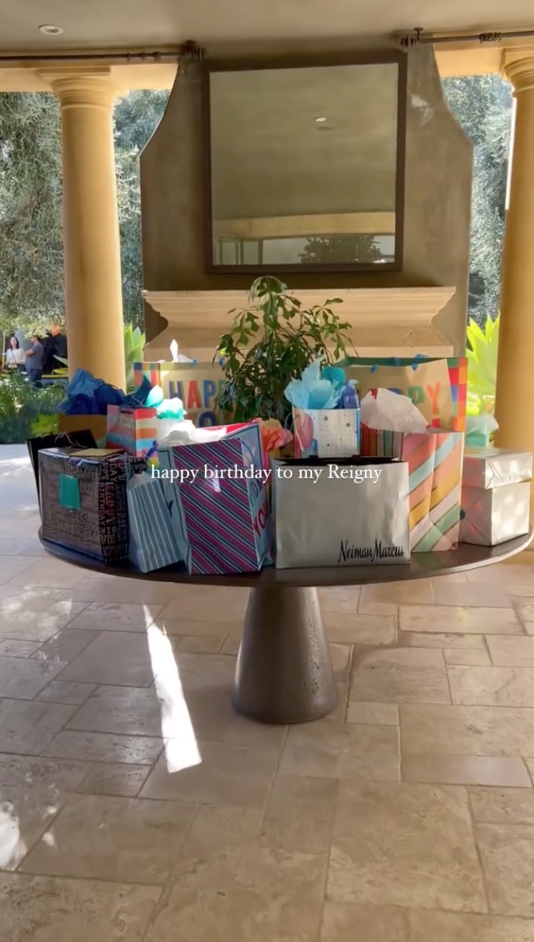 A Neiman Marcus bag could be seen near the edge of a tabletop that was filled with birthday gift bags and neatly wrapped presents
