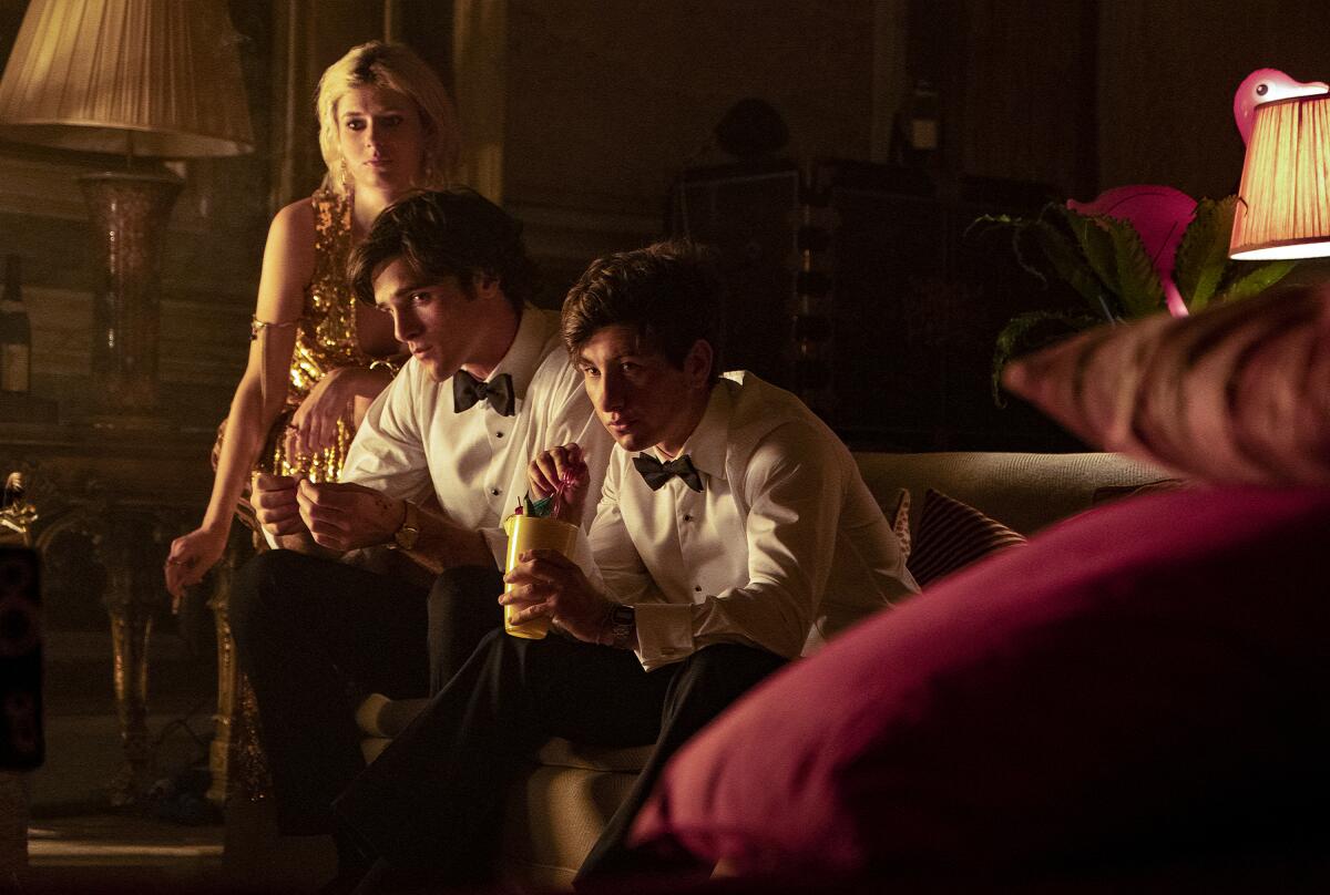 A young woman and two young men in formal wear sit in a well-appointed room in "Saltburn."