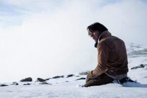 A man sits on a snowbank.