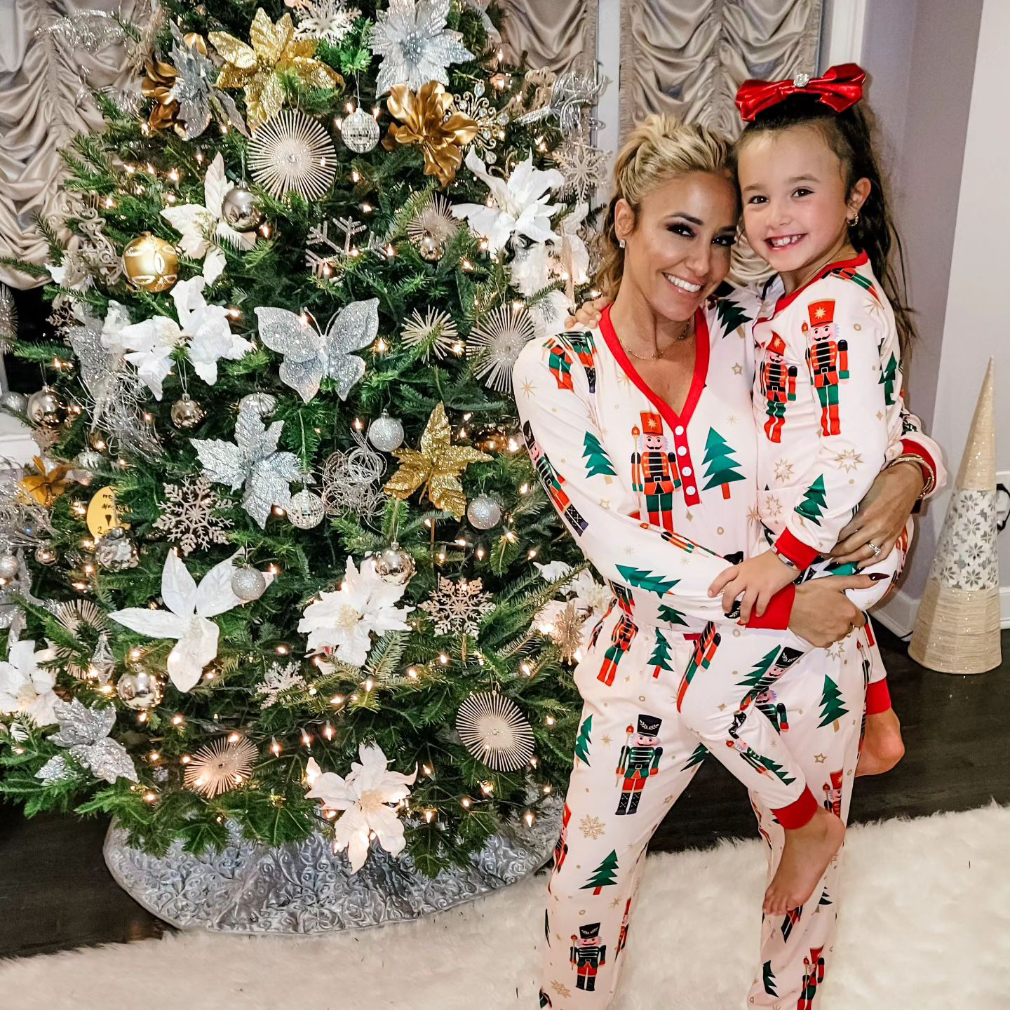 Danielle posed in front of her shiny tree with her daughter wearing matching PJs