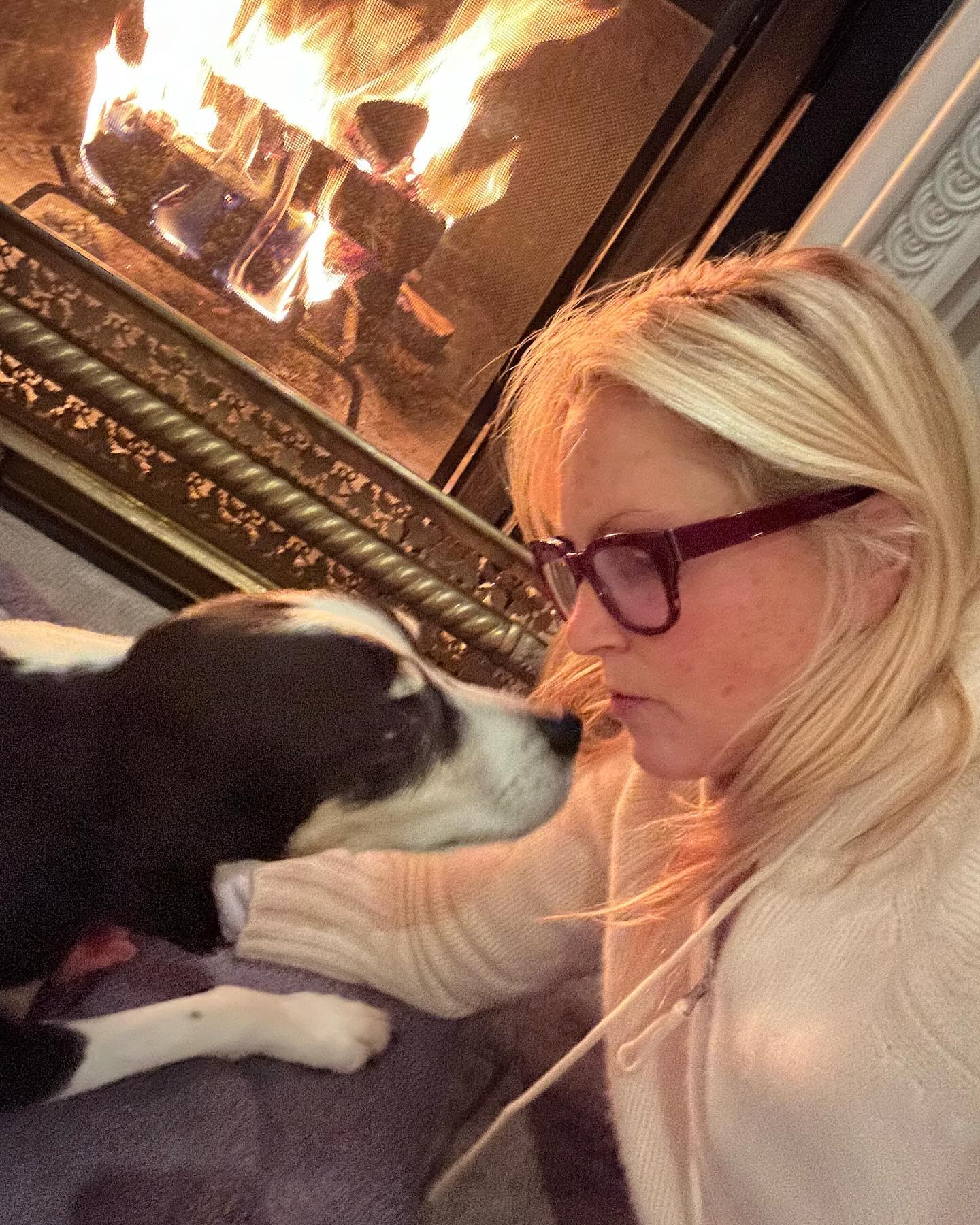 Ali cozied up to their dog against a roaring fire