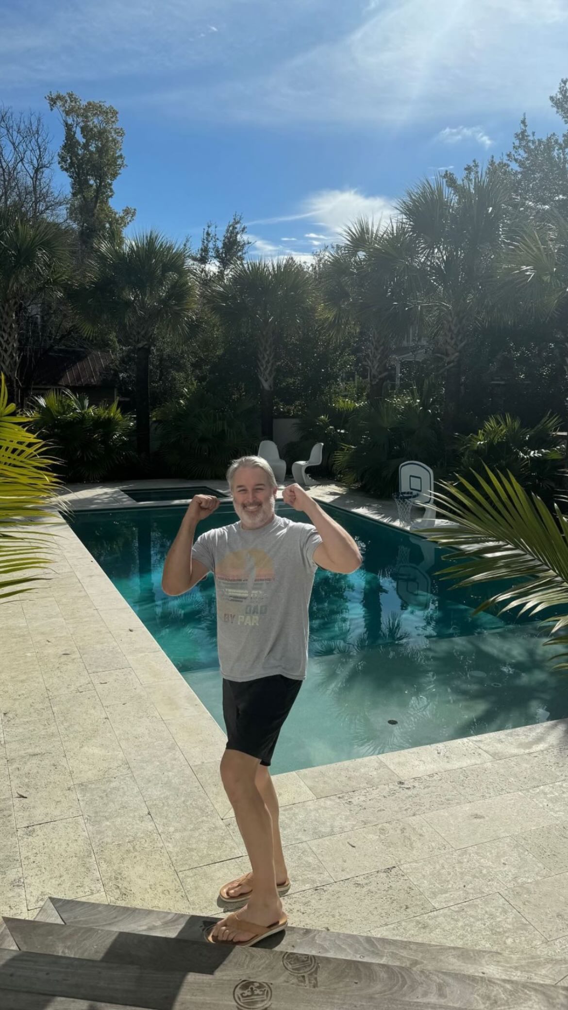 Tim was seen flexing on the steps of a pool on vacation in a T-shirt and black shorts