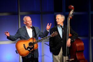 Tom and Dick Smothers perform on a show with a guitar and a double bass.