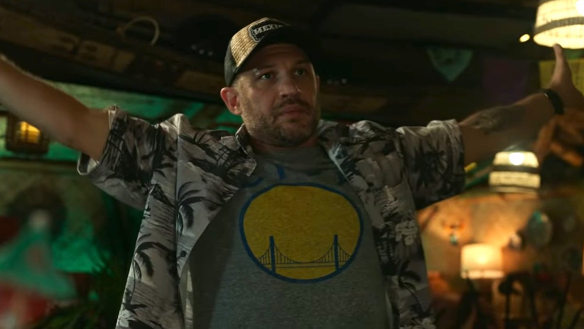 Eddie Brock in a trucker hat with his arms held out wide in Spider-Man: No Way Home