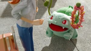 A Bulbasaur presents a lei to a hotel guest using its vines.