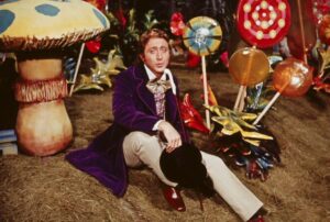 Gene Wilder as Willy Wonka, sitting amongst giant candies.