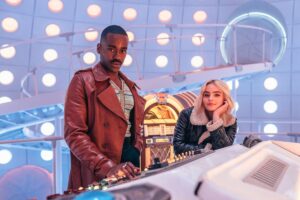 The Doctor poses suavely at the controls of his TARDIS while Ruby Sunday leans on the console and smirks in an image from the Doctor Who Christmas special.