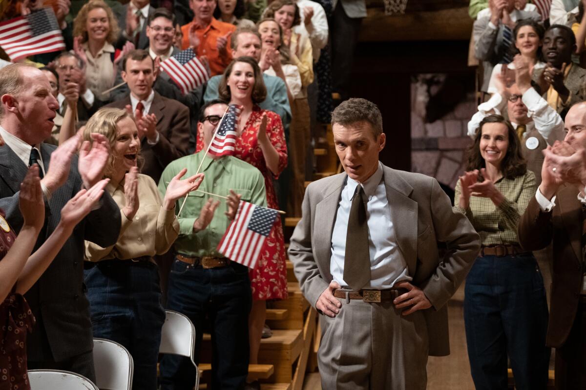 Cillian Murphy walks among a flag-waving crowd in a scene from "Oppenheimer."