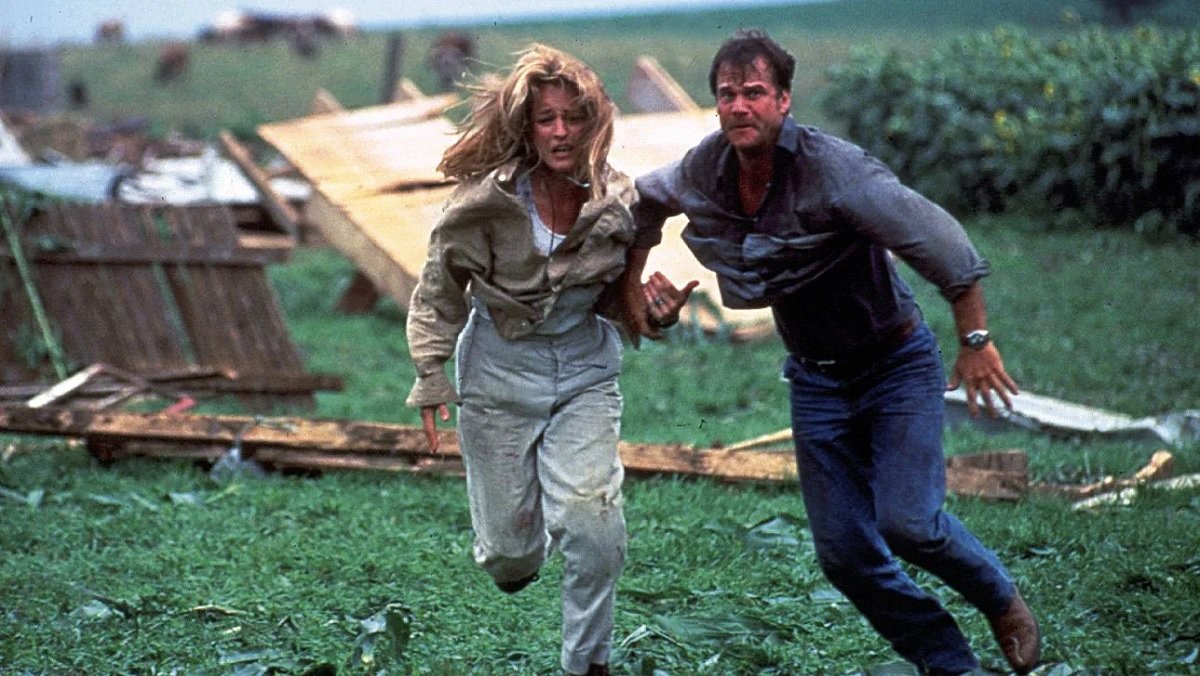 Helen Hunt and Bill Paxton run amid debris in the 1996 movie Twister.